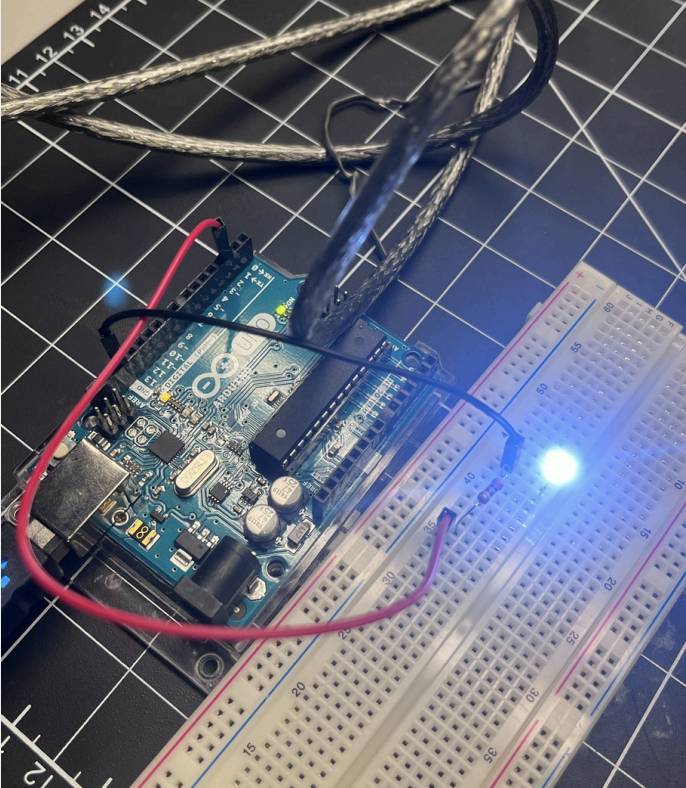 A top view of the Arduino UNO and breadboard connection, highlighting the clear wiring between digital pins, resistors, and LED output.