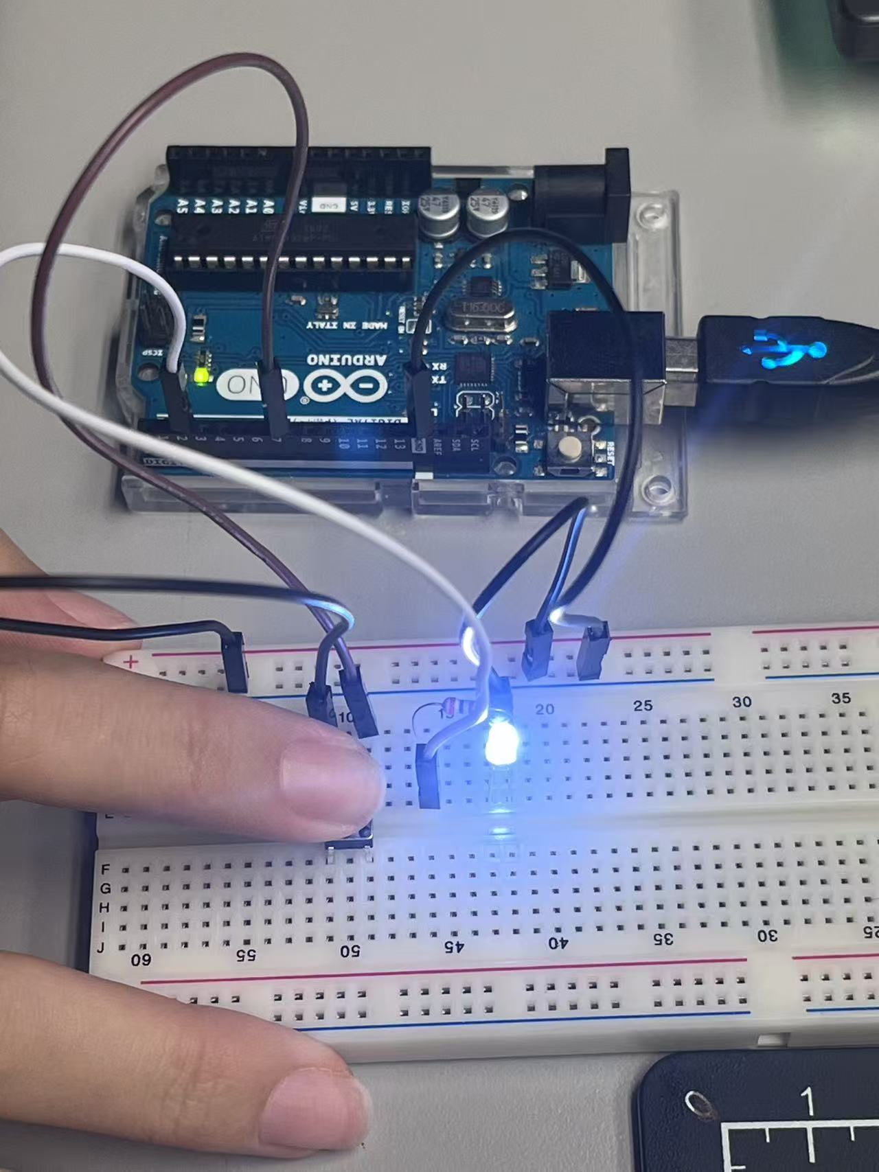 A push button is added to the circuit, enabling basic user input to control the LED’s on-and-off behavior.